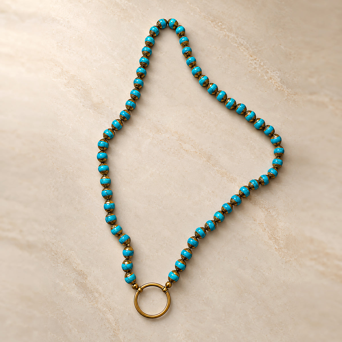 The Nepalese Turquoise laid on cream marble, turquoise beads capped in brass with a round gold loop